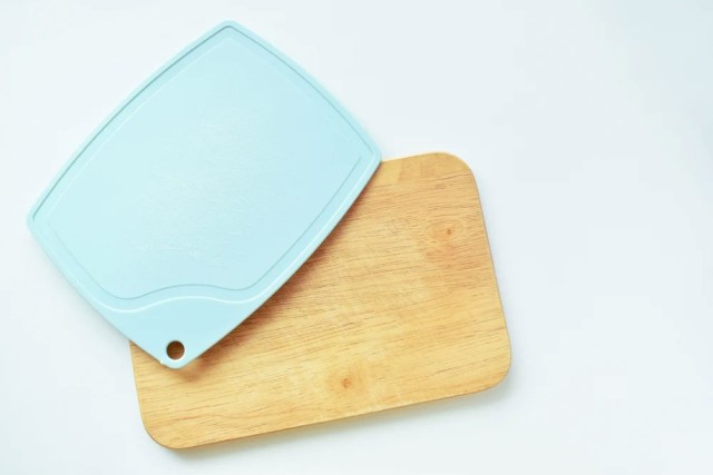 a plastic and a wood cutting board sit next to each other on a white background