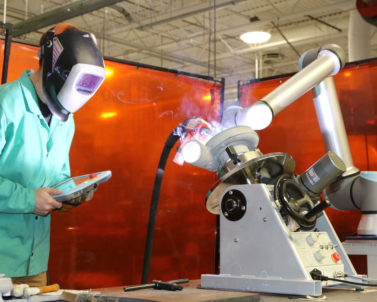 engineer using robot arm to work on cold welding an automotive part