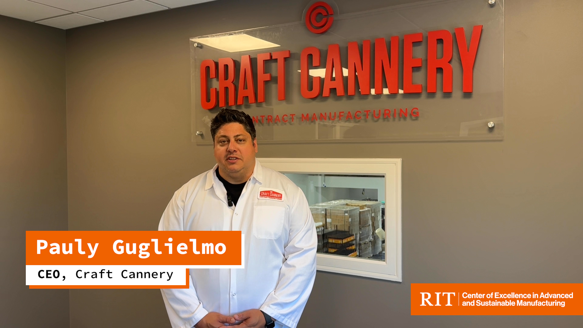 Pauly Guglielmo in a white lab coat in front of a small window leading to the productin floor