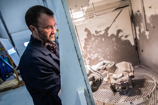 A researcher cleaning metal manufacturing parts.