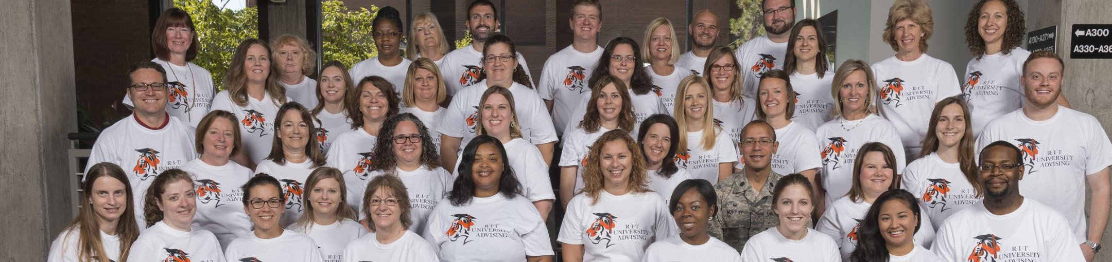 A group of people standing for a photo wearing shirts that say RIT University Advising