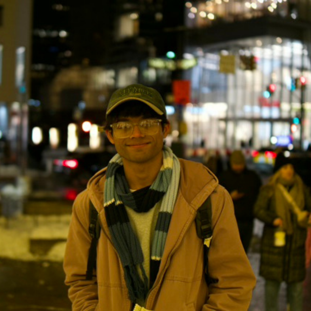 photo of a young man in a hat standin gon a street