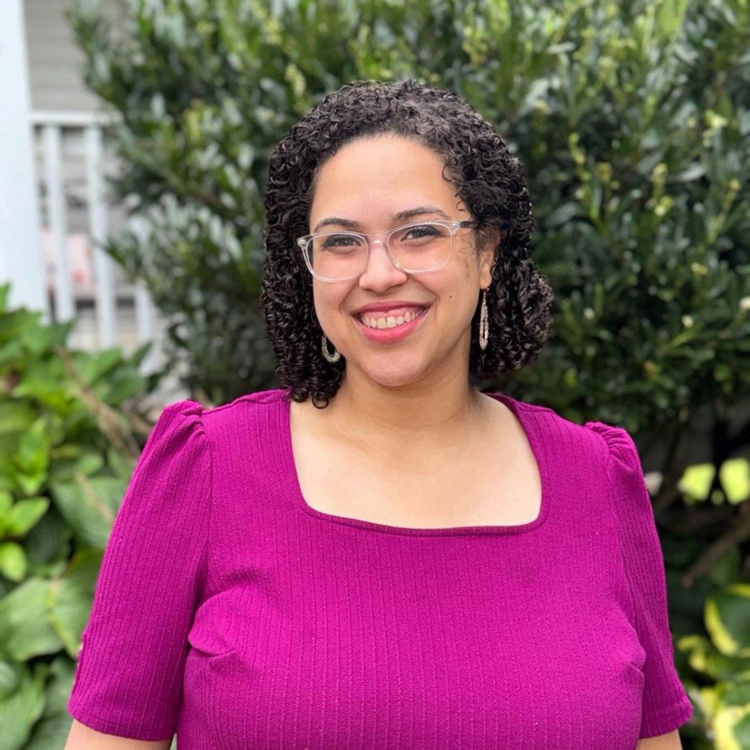 women in a pink shirt infront of a bush 
