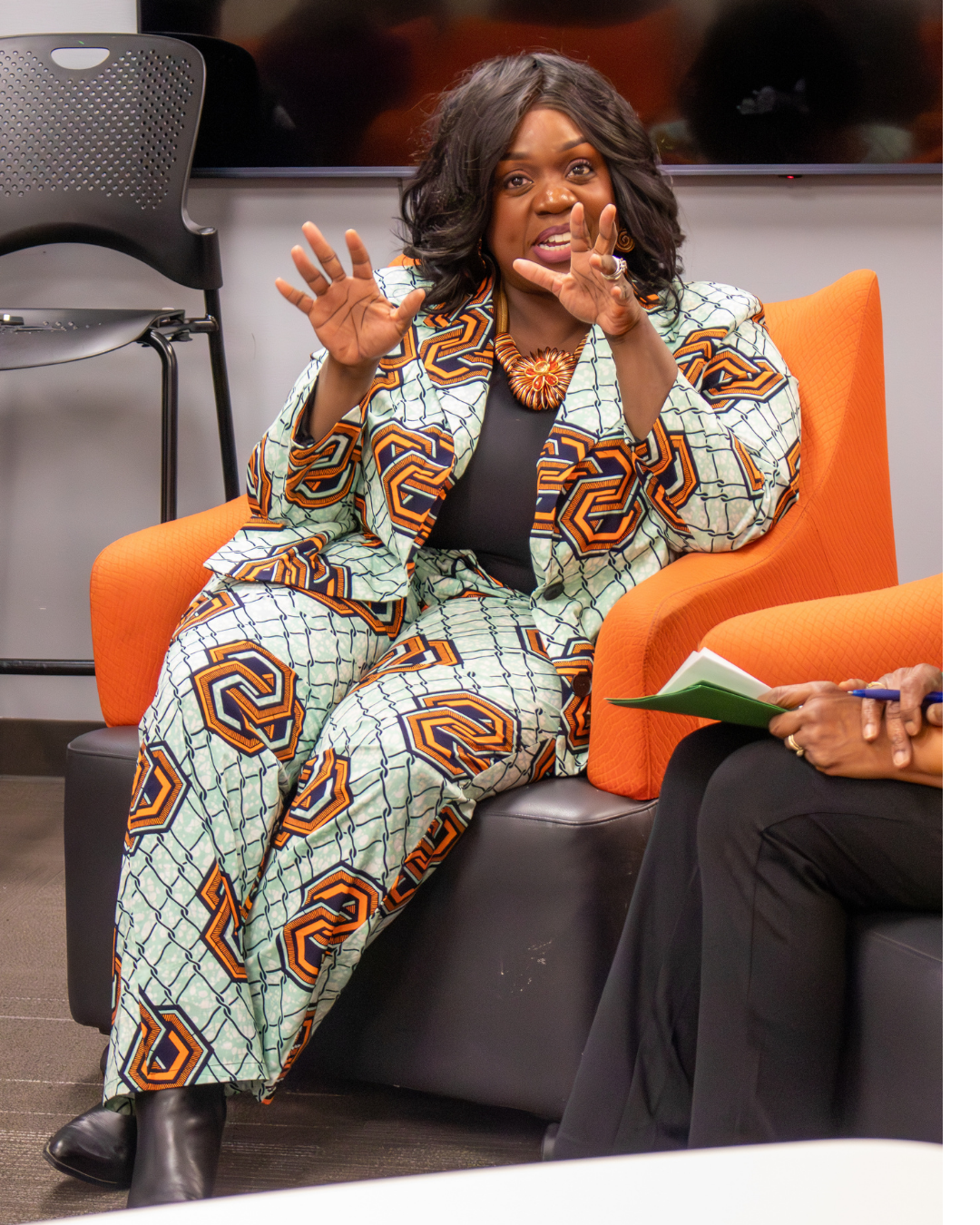Photo of a woman in a patterned suit sitting and talking 