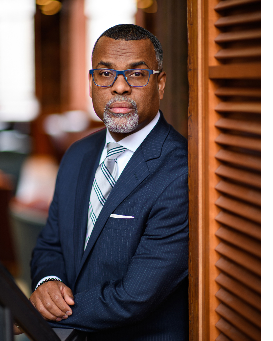 Man in a suit leaning against a shutter window