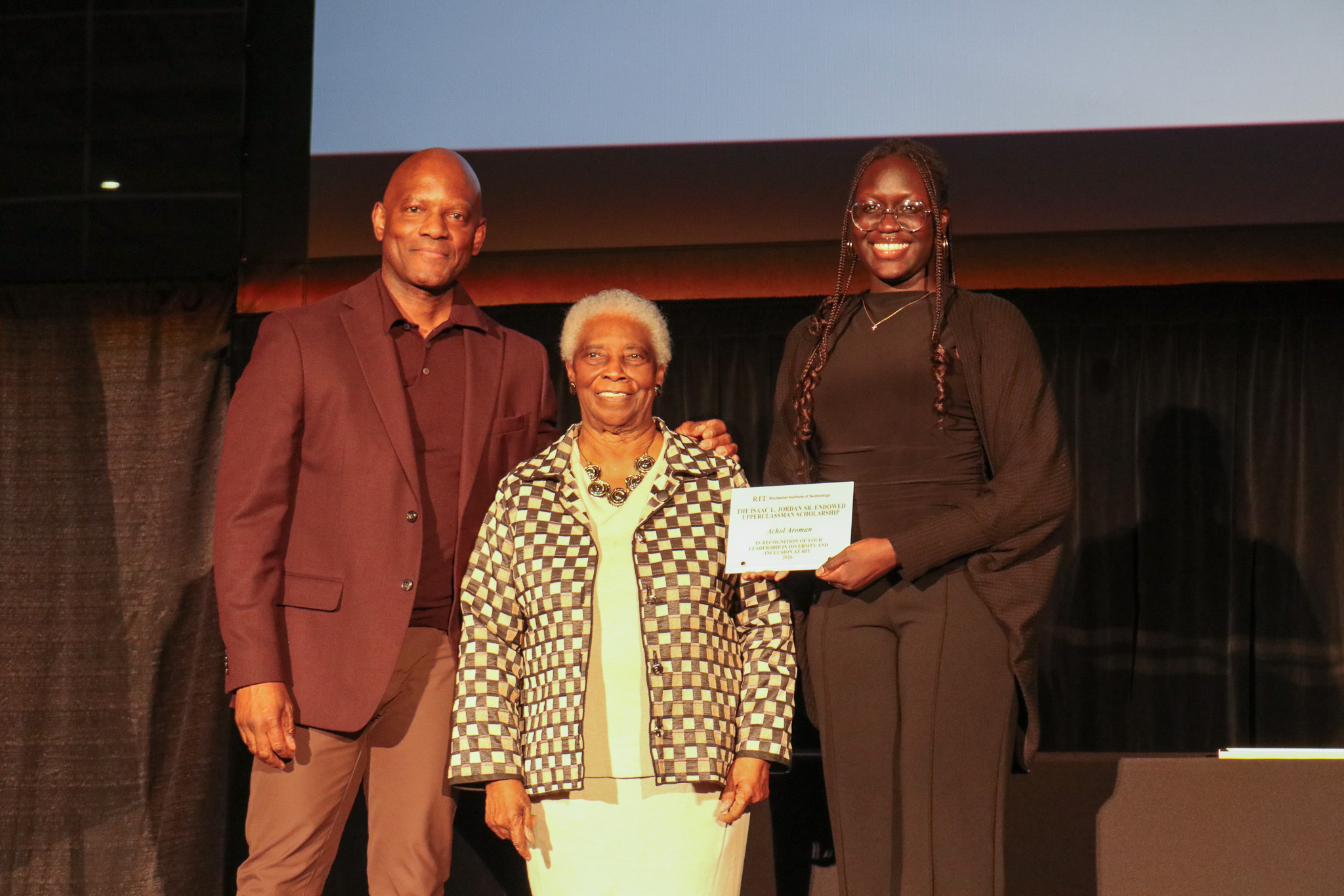 Grpup of three people on stage presenting an an award