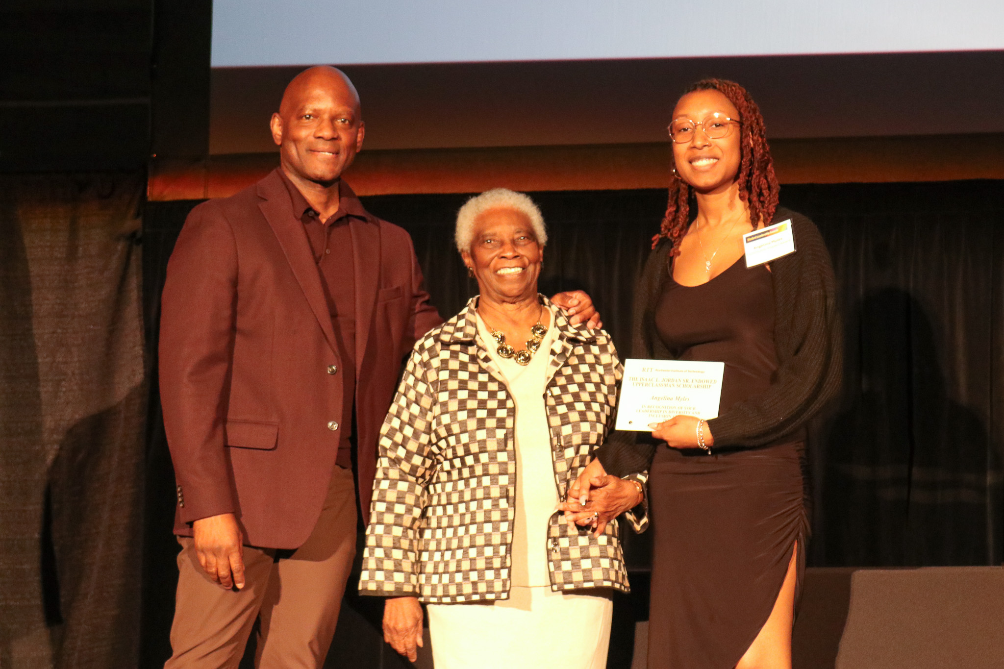 Grpup of three people on stage presenting an an award