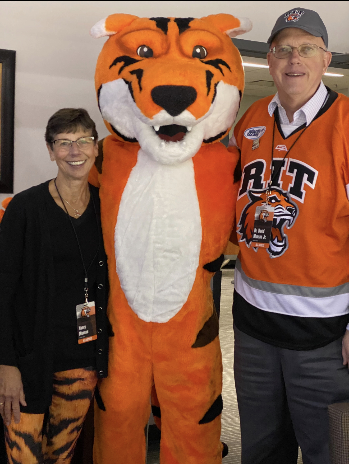 a man and women standing with RIT Tiger mascot
