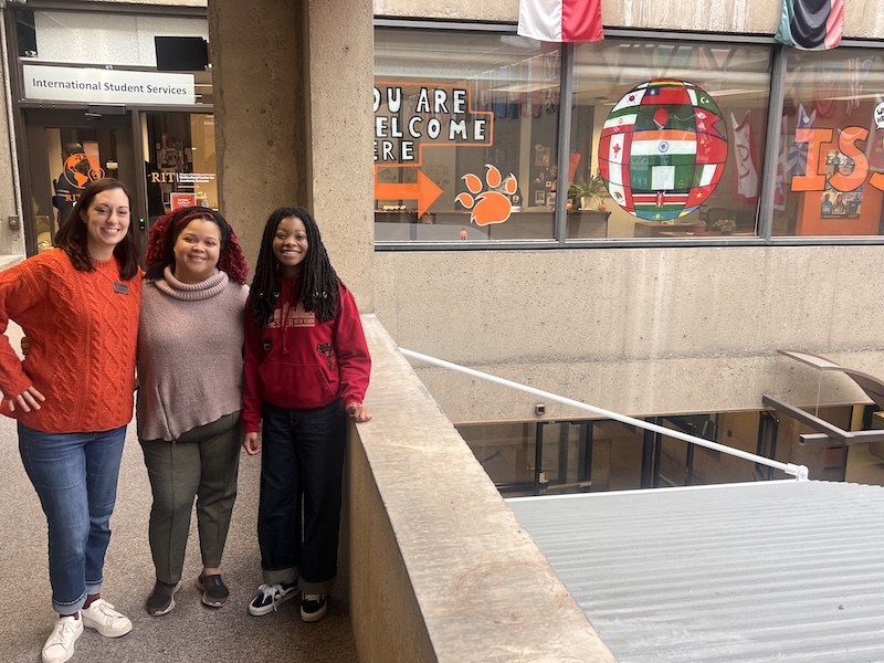Three women in front of a mural painted on a window