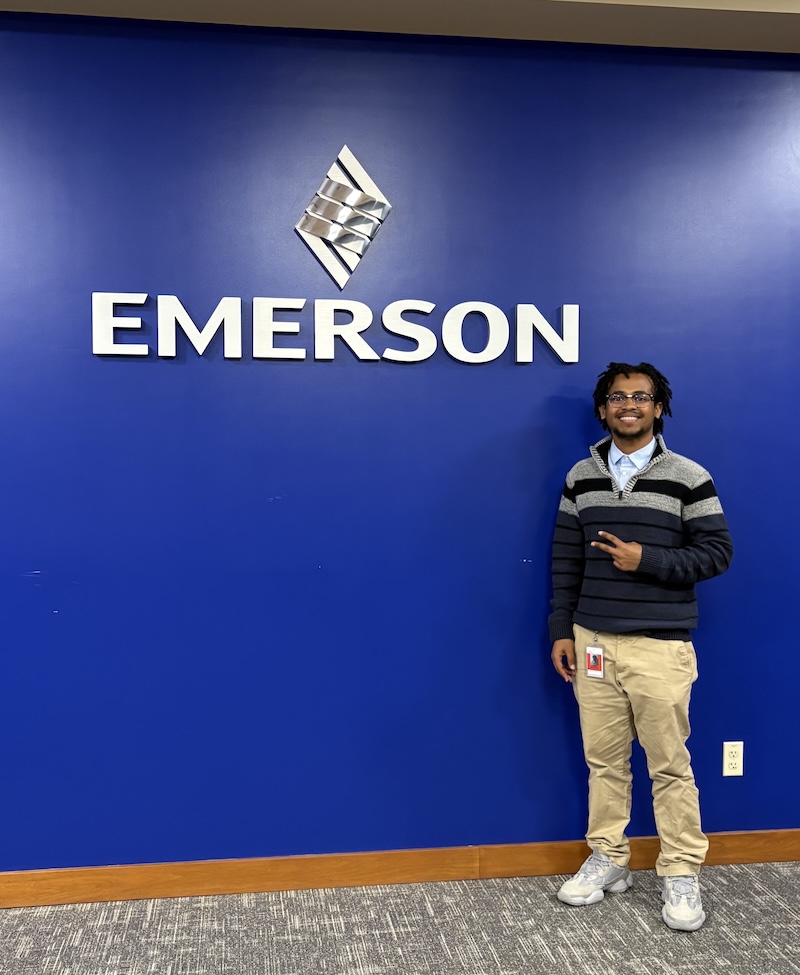 Student standing in front of Emerson sign