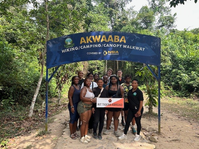 Group photo of people outside under a blue sign