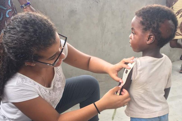 Woman measures arm of child with strip to determine anemia.