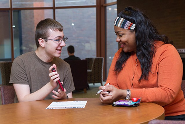 student and staff member talking at a table.