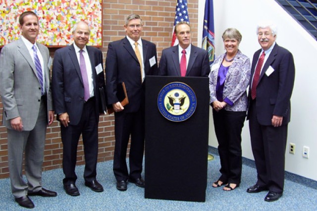 People posing in front of flags at podium