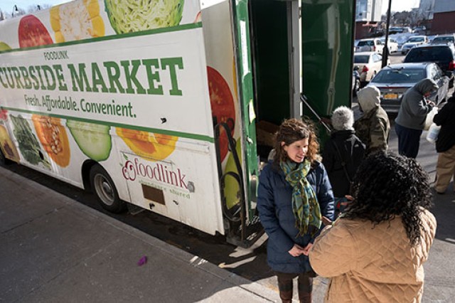 A photo of Foodlink's curbside market truck. People stand around the truck talking.