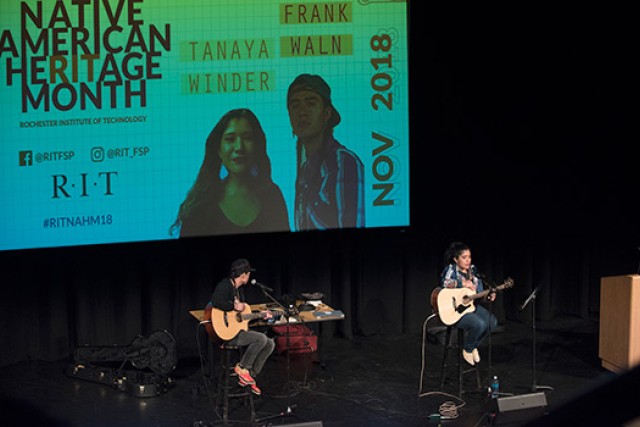 two people playing guitar on stage.