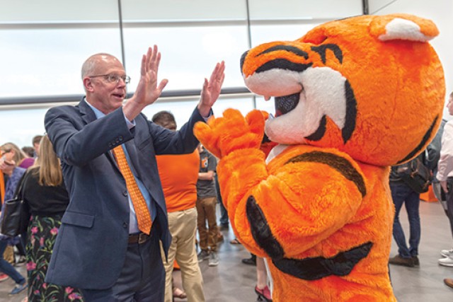 RIT President high fiving mascot