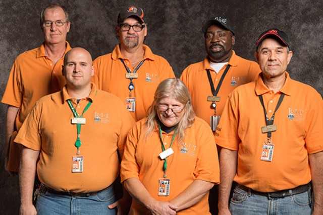 Team poses together in matching orange polos.