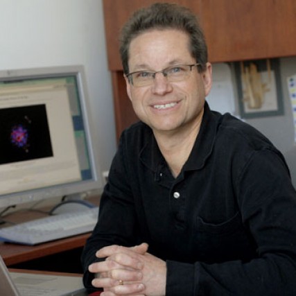 Professor sitting in office next to computers