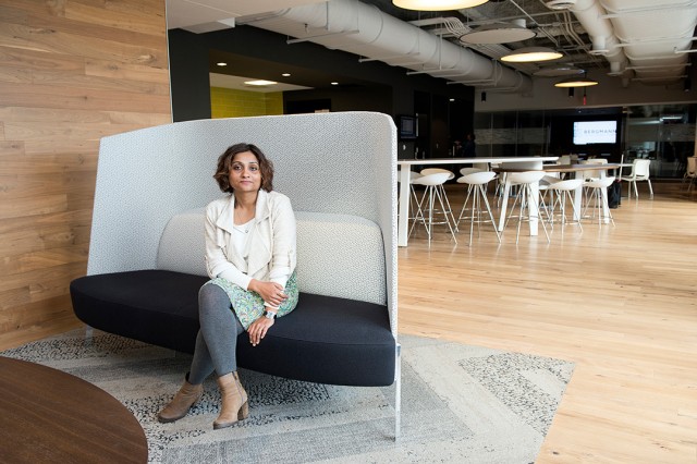 woman in gray tights and white top sits in open-concept lounge area