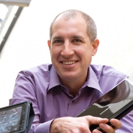Head-and-shoulders view of professor holding a closed laptop