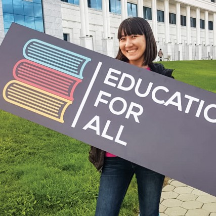 Woman holds sign that reads: Education For All.