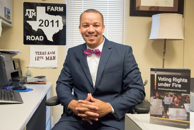 Man wearing suit sits at office desk.