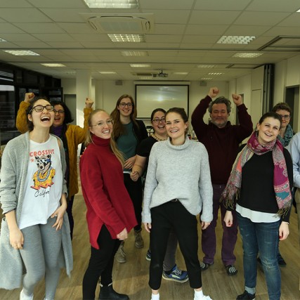 Group of men and women standing in classroom.