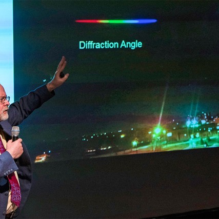 Man in suit gestures toward presentation.