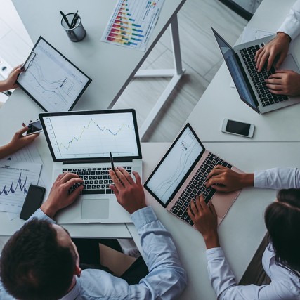 Overhead view of four people working on  laptops.