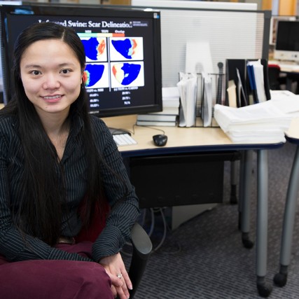 Woman wearing black blouse sits in front of desk with computer.