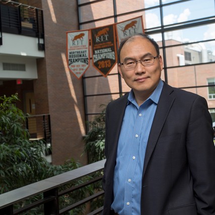 Man wearing suit stands in upperlevel lobby.