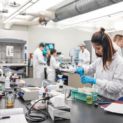 Student in lab coat works with pipette.