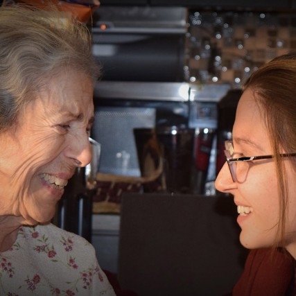 Senior citizen and young woman laugh together.