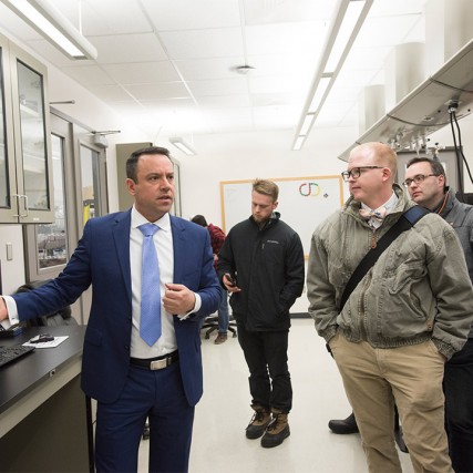 Man in suit leads tour of lab facility.