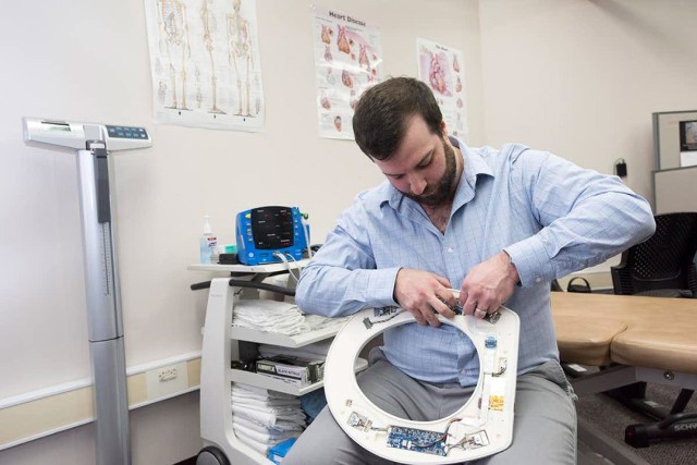 Researcher afixes sensors to underside of toilet seat.