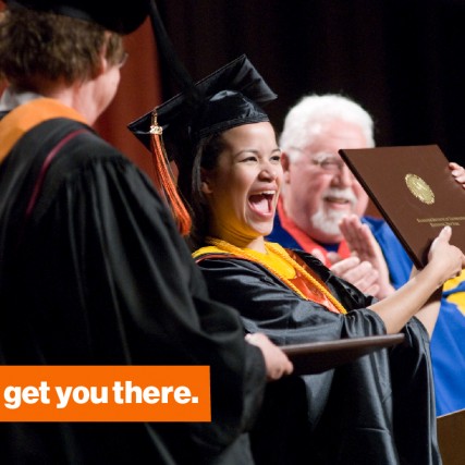 A Saunders graduate student proudly presents her diploma at graduation. 