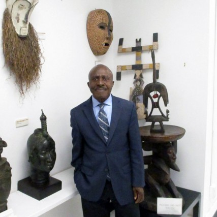gallery owner standing in front of African art pieces.