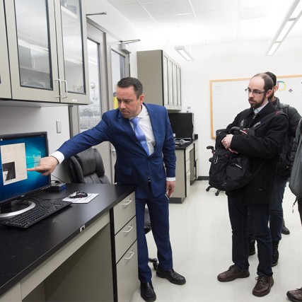 researcher giving demonstration of computer equipment to visitors.