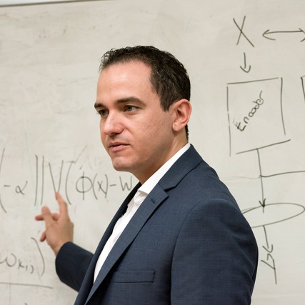 researcher pointing at equations on dry-erase board.
