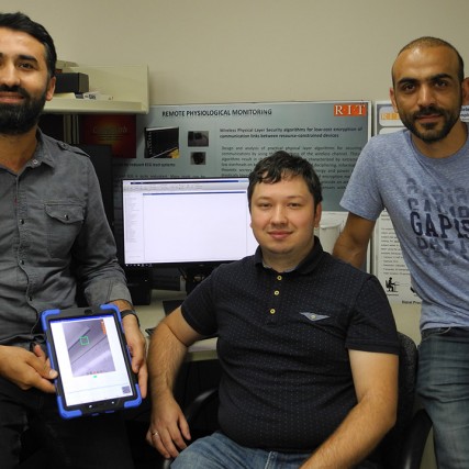 three researchers with one holding a tablet.