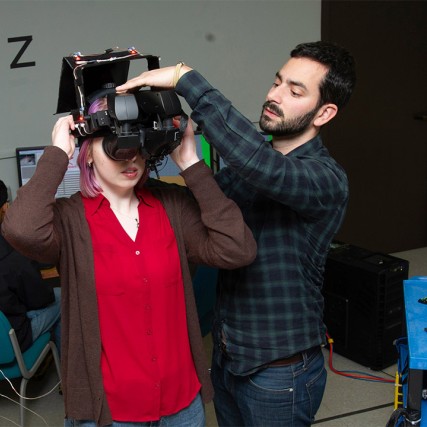 professor helping student put on virtual reality headset.