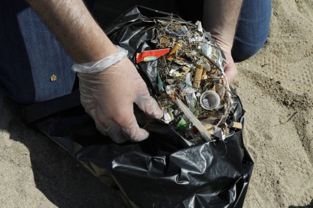 hands holding garbage bag full of debris.