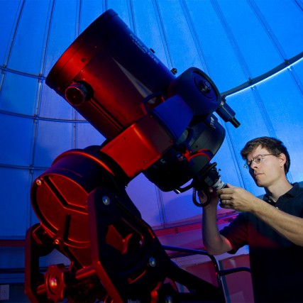 man looking at giant telescope in an observatory.