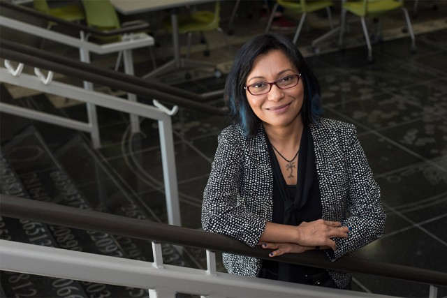 professor standing on stairs in atrium of college.