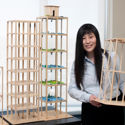 professor holding wooden models of skyscrapers.