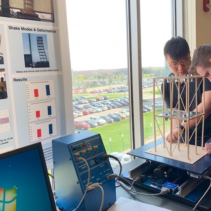 students testing a model structure on equipment to test how it withstands shaking.