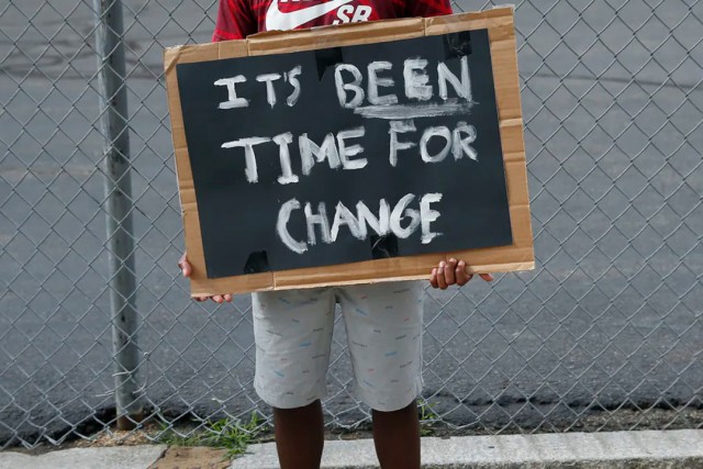 person holding a sign that reads: It's been time for change.