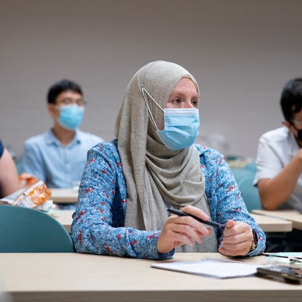 people wearing face masks seated at long tables attending a workshop.