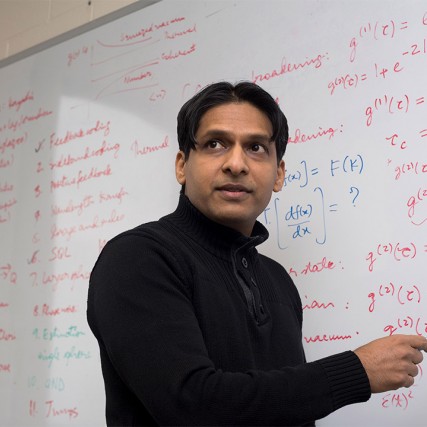 professor writing math equations on a dry-erase board.